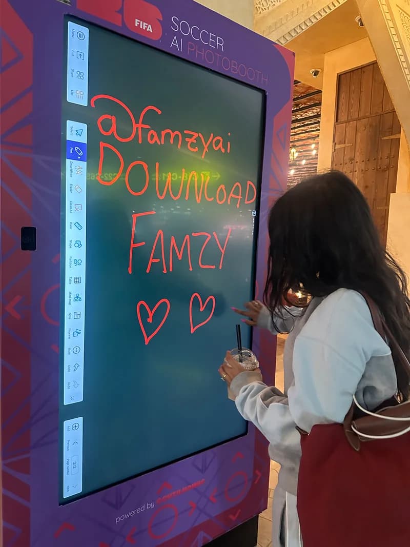 Alayna drawing hearts beneath a handwritten Famzy message on a digital screen